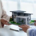 Two professionals holding a modern residential house model, representing luxury architecture design services in Ludhiana by Violet Bricks.